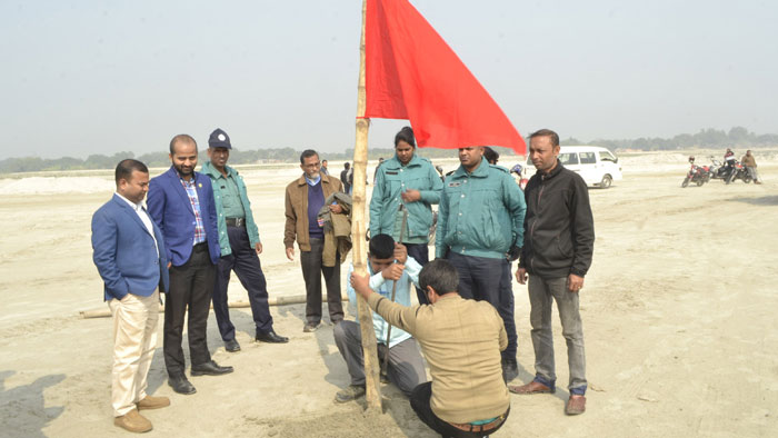 নবগঙ্গা চরে বালু তোলা নিষিদ্ধ করে লাল নিশান টাঙ্গিয়ে দিচ্ছে প্রশাসন। ছবি: একুশে টেলিভিশন